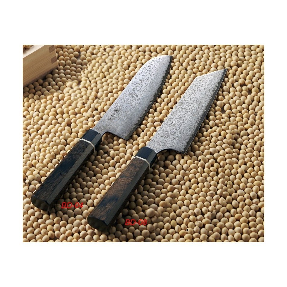 Kaksi Suncraft Senzo Damascus Black Kiritsukeveistä 16,5 cm esillä soijapapujen päällä, korostaen veitsien ainutlaatuista teräkuviointia.