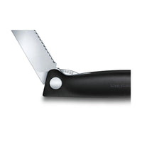 Victorinox Taittuva Retkiveitsi osittain avattuna, esittelee terän lukituspainikkeen ja sahalaitaisen terän yksityiskohdat.